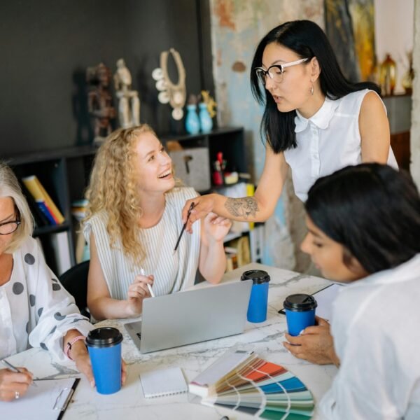 A diverse group of women collaborating in a modern office setting, discussing ideas and working together.